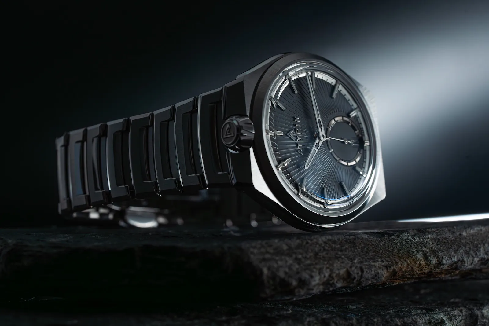 Atypik AT01 with crown at 12 o'clock, side-lit on stone